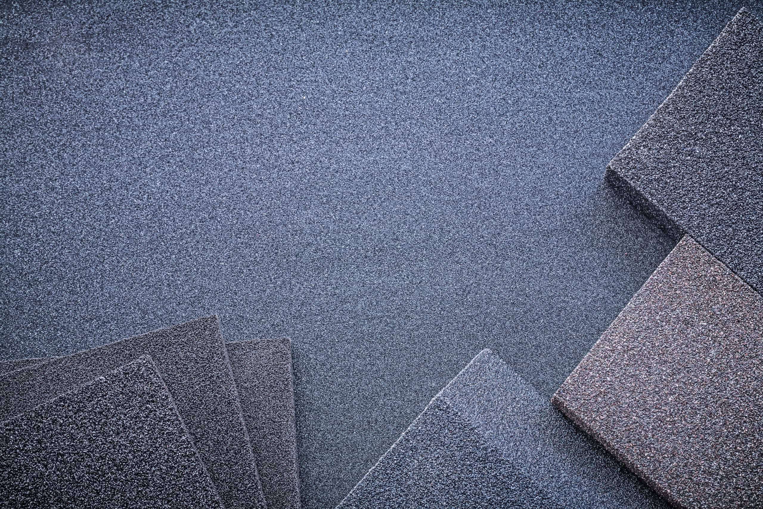 Top view of dark grey abrasive sanding sponges and emery paper sheets used for hardwood floor sanding services in Ocala, FL.