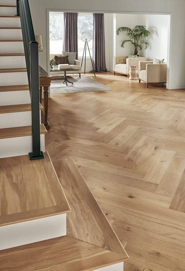 Flooring Installations 9 Light natural oak herringbone pattern hardwood flooring installation in a modern living space featuring matching wood staircase steps in Gainesville, FL.